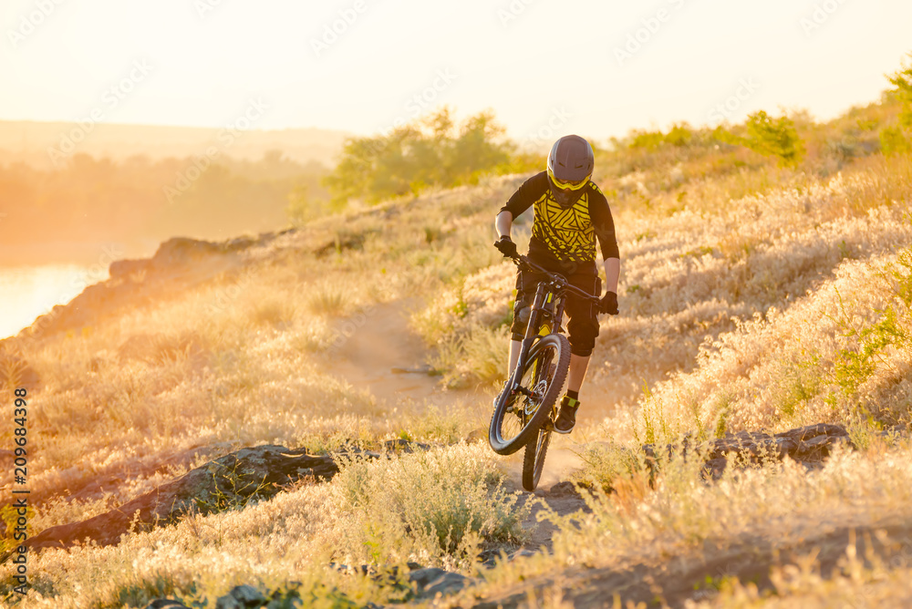 Cyclist Riding the Mountain Bike on the Summer Rocky Trail at the Evening. Extreme Sport and Enduro Cycling Concept. Cyclist Riding the Mountain Bike on the Summer Rocky Trail at the Evening. Extreme Sport and Enduro Cycling Concept.