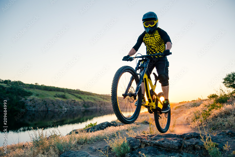 Cyclist Riding the Mountain Bike on the Summer Rocky Trail at the Evening. Extreme Sport and Enduro Cycling Concept. Cyclist Riding the Mountain Bike on the Summer Rocky Trail at the Evening. Extreme Sport and Enduro Cycling Concept.