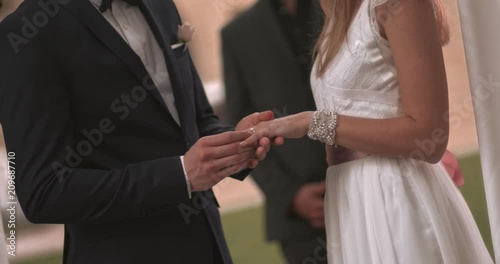 Bride and groom exchanging wedding rings and holding hands photo