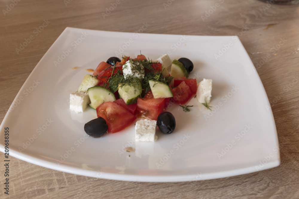 Greek salad with fresh vegetables, feta cheese, tomatoes, herbs and black olives. Cold appetizer, Vegan food and well-balanced meal.