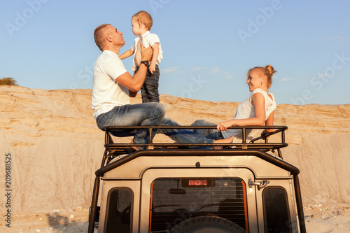 Portrait of a young family with son on the car roof. © Petro