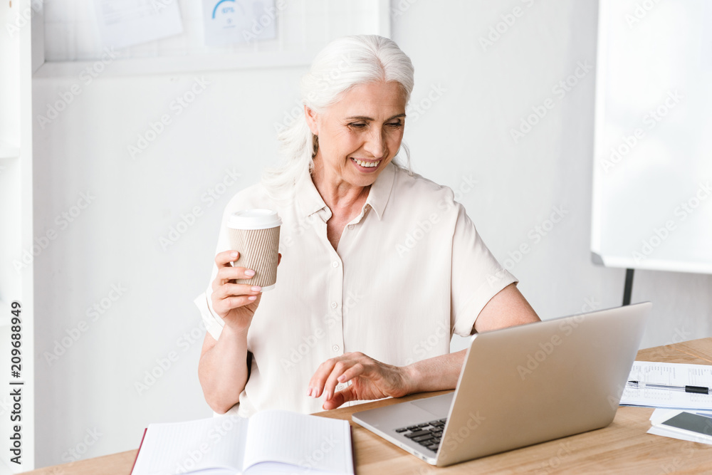 Smiling mature business woman working on laptop Smiling mature business woman working on laptop