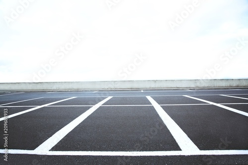Empty outdoor parking lot space marked with white lines. Can accommodate car a lot.