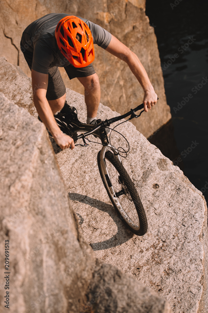 Naklejka premium high angle view of trial biker balancing on rocks outdoors