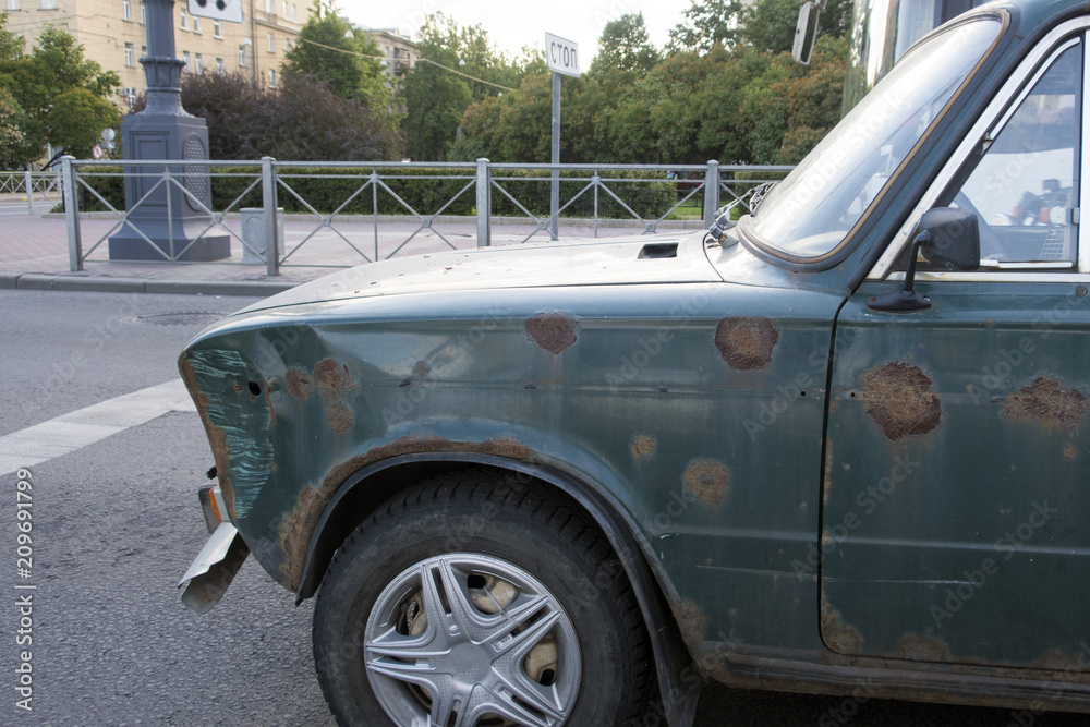 Very old and rusty car in the city on the road