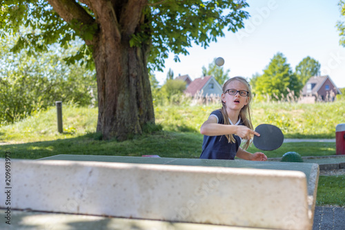 Ein Schulmädchen spielt Tischtennis. Sie konzentriert sich darauf, den Ball zu treffen photo