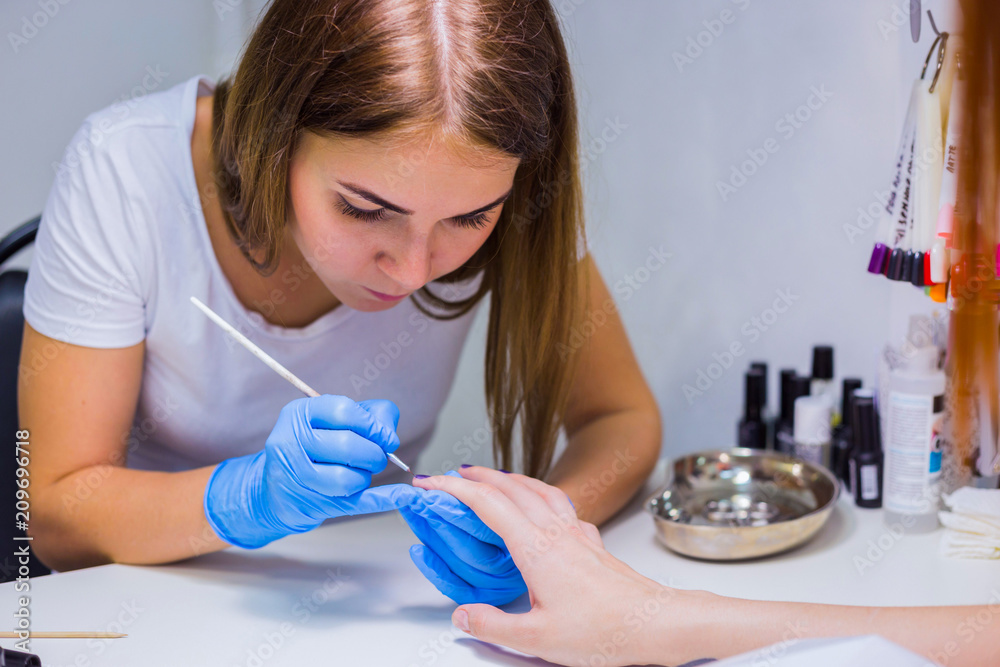 Manicurist master makes manicure on young woman hand