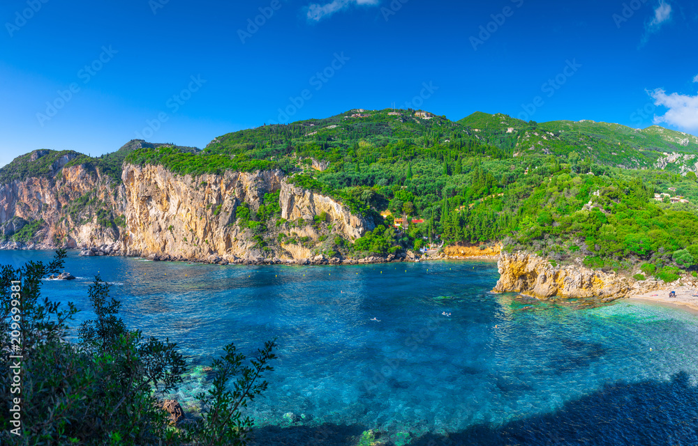 Beautiful summer panoramic seascape. View of Paleokastritsa famous beach in close bay with crystal clear azure water on Corfu island, Ionian archipelago, Greece.