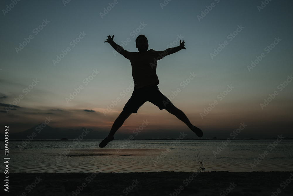 .Young man on vacation in the Gili Islands enjoying a colorful sunset in Indonesia. Jumping for the picture. Photograph and vacation. .Young man on vacation in the Gili Islands enjoying a colorful sunset in Indonesia. Jumping for the picture. Photograph and vacation.