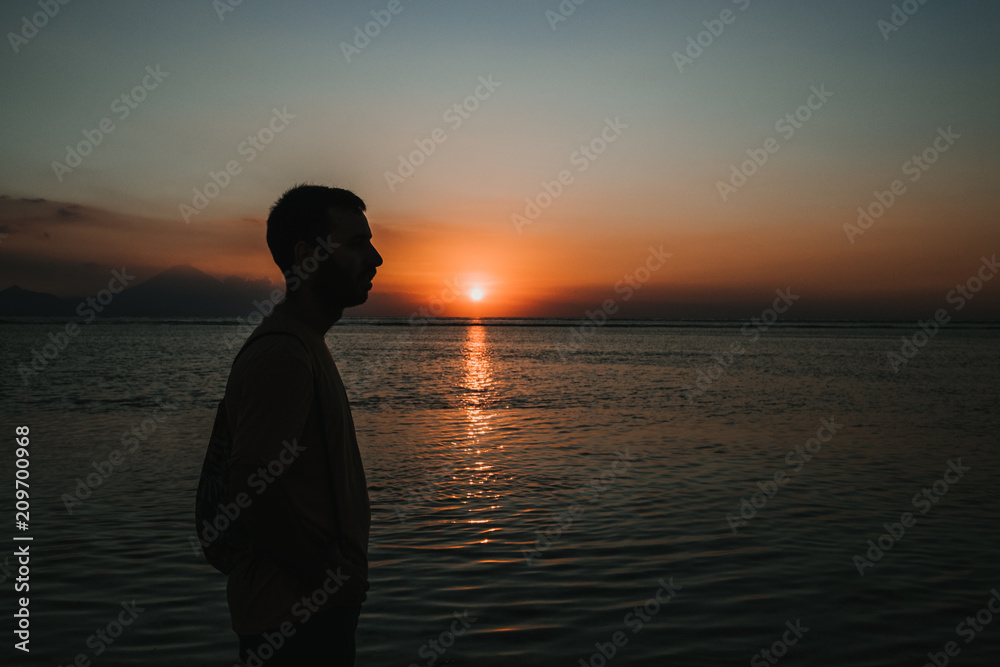 .Young man on vacation in the Gili Islands enjoying a colorful sunset in Indonesia. Photograph and vacation.