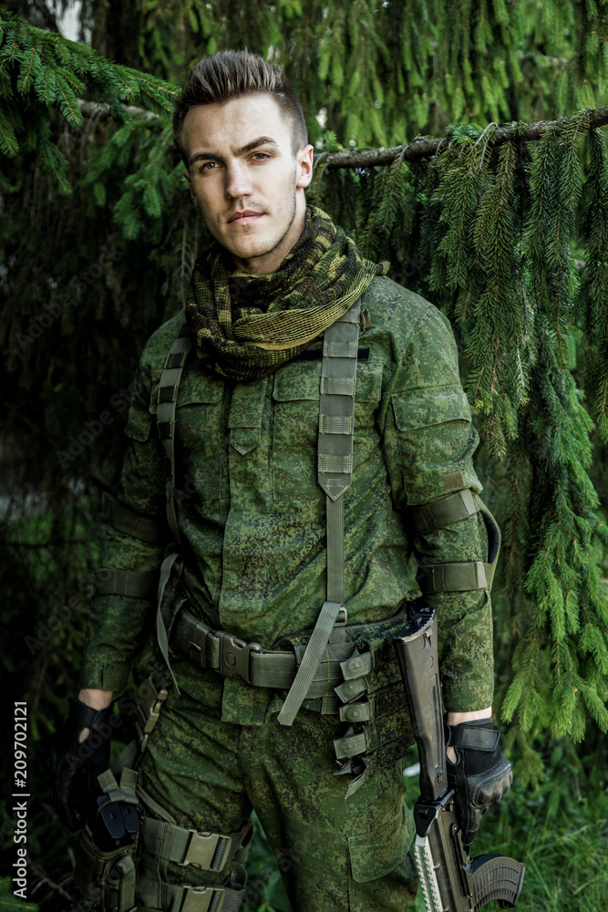 Young male military soldier with a rifle posing outdoors