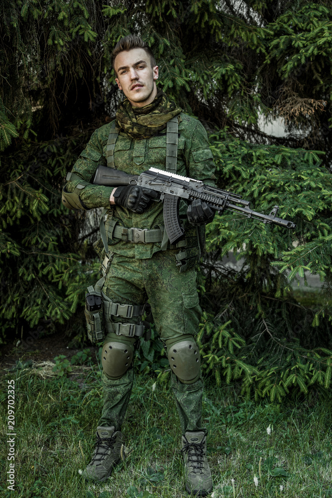 Young male military soldier with a rifle posing outdoors