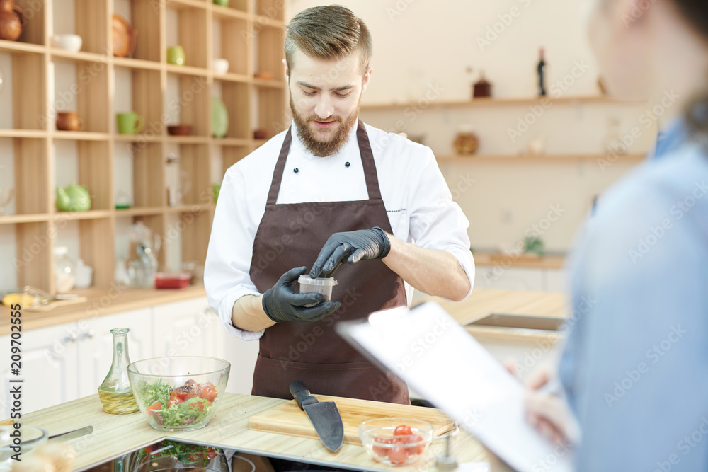 Fototapeta premium Portrait of young professional chef preparing ingredients for culinary masterpiece in modern restaurant kitchen, copy space