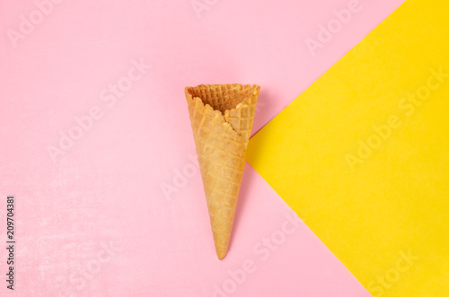 Ice cream waffle cone over light yellow and sweet pink background with copy space for text, logo or wordings insertion or decoration, colourful summer cold sweet snack concept © artissp