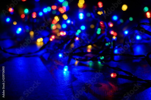 Blurred glowing red, green, blue and orange christmas lights on a wooden table with copy space for use as a christmas background