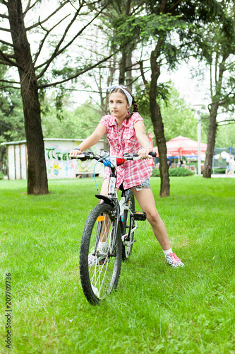 Girl riding her bicycle in the park feeling good 