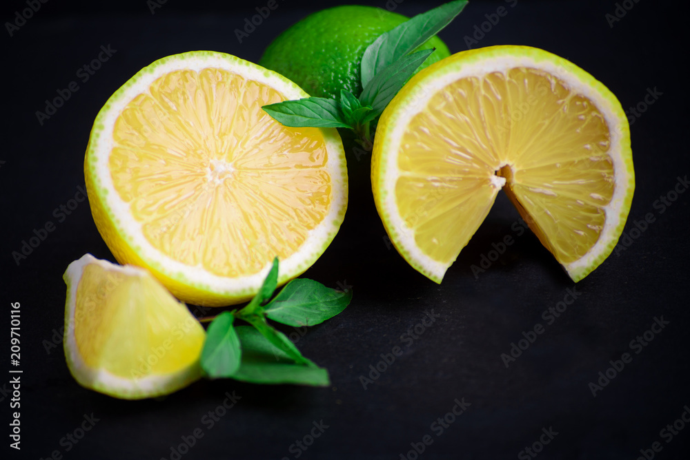 Ripe and juicy lime and lemon with a sprig of mint on a dark table Ripe and juicy lime and lemon with a sprig of mint on a dark table