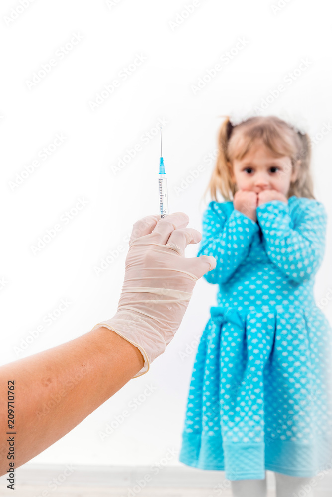 Doctor holds syringe to vaccinate sick baby with injection. Crying and fear a little patient before the injection.