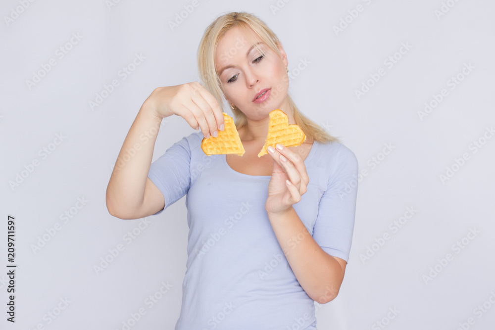 Happy blond woman holding in hands and showing belgian waffles Happy blond woman holding in hands and showing belgian waffles
