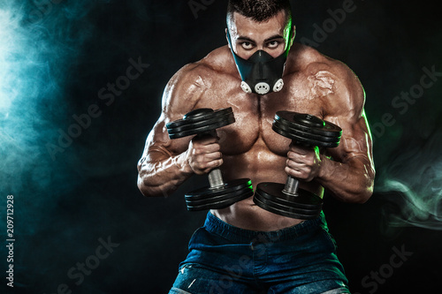 Muscular young fitness sports man, bodybuilder in training mask. Workout with dumbbell in fitness gym © Mike Orlov