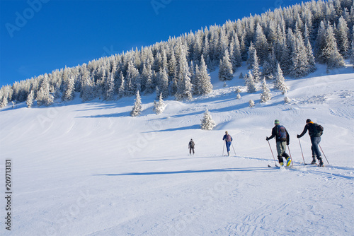Foto Gruppe Skifahrer in Winterlandschaft in den Alpen mit Sonne und blauen Himmel