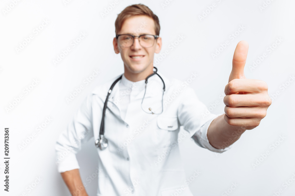 Portrait of a young doctor, on a white background, which shows a hand gesture super, class, Intern in the workshop, with a stethoscope on the neck, for advertising, text insertion Portrait of a young doctor, on a white background, which shows a hand gesture super, class, Intern in the workshop, with a stethoscope on the neck, for advertising, text insertion