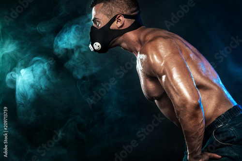 Muscular young fitness sports man in training mask. Workout with dumbbell in fitness gym © Mike Orlov