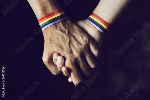 men holding hands with rainbow-patterned wristband photo