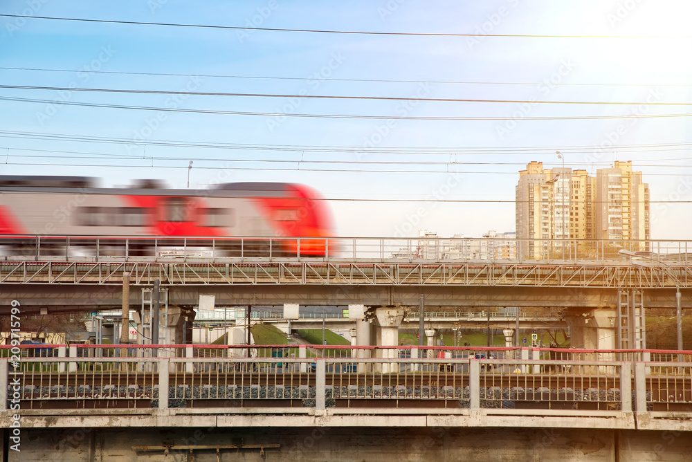 Fast modern metro train on the city background. Sunny day with the clear sky. Blurred motion.