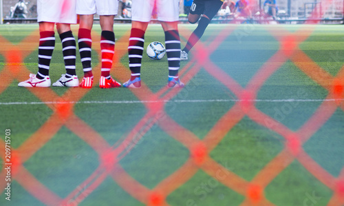 Fotografie The footballer is about to kick the ball from the free kick, wit