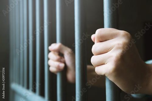 Vászonkép Man in prison hands of behind hold Steel cage jail bars
