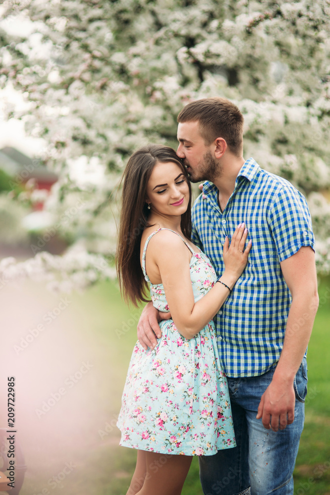 Young couple in love resting in the blooming garden. white blooming trees Young couple in love resting in the blooming garden. white blooming trees