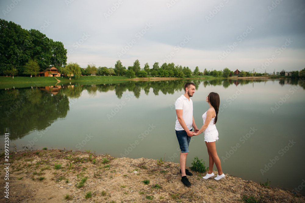 Dating in park. Love couple standing together on ground near the lake. Romance and love Dating in park. Love couple standing together on ground near the lake. Romance and love