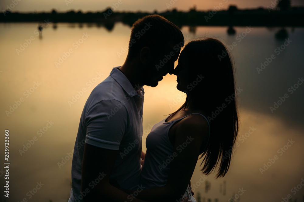 Silhouette of beautiful couple. lake in background