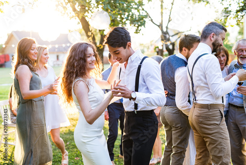 Photo Guests dancing at wedding reception outside in the backyard.