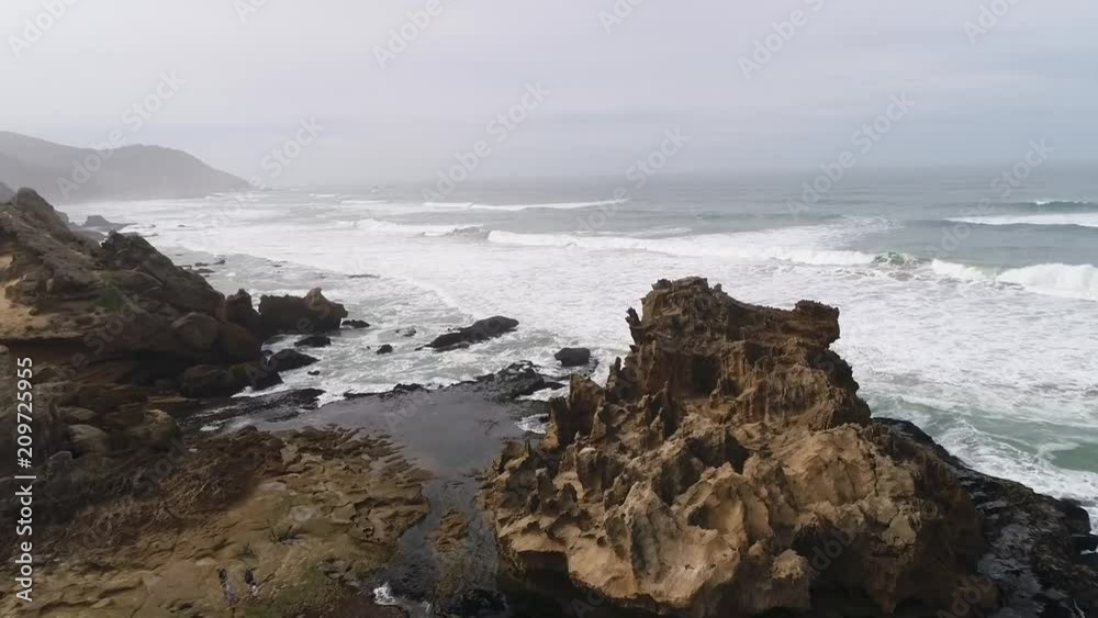 Aerial drone shot flying over dangerous rocky cliffs and out over choppy waves in the ocean in South Africa Aerial drone shot flying over dangerous rocky cliffs and out over choppy waves in the ocean in South Africa