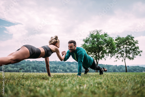 Couple standing in a plank position holding each other hand.