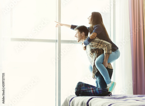 Loving young couple looking through window in hotel room photo