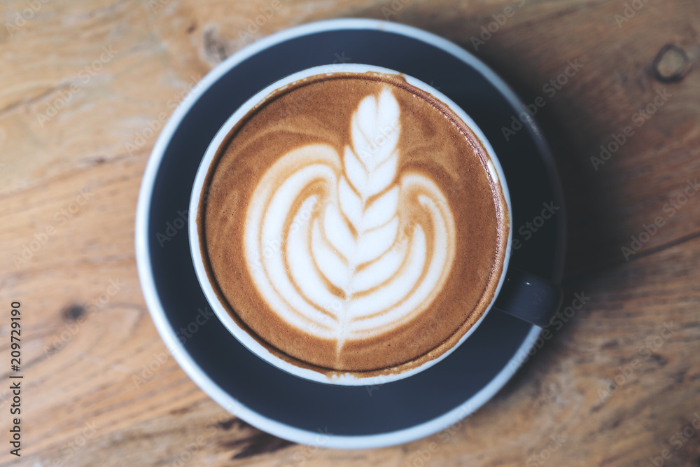 Top view image of a blue cup of hot latte coffee with latte art on vintage wooden table in cafe Top view image of a blue cup of hot latte coffee with latte art on vintage wooden table in cafe