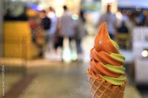 Milk Tea and Green Tea Two-tone Soft Serve Ice Cream Cone, Blurred Shopping Mall in Background 