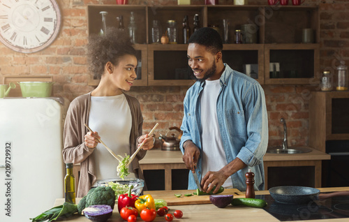 Happy black couple preparing salad in kitchen