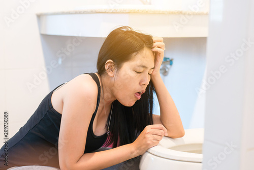Asian woman with morning sickness Pregnant female nausea  into the toilet bowl
