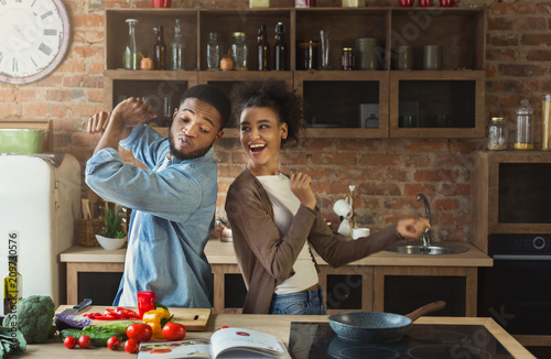 Black couple dancing near table with food in kitchen photo