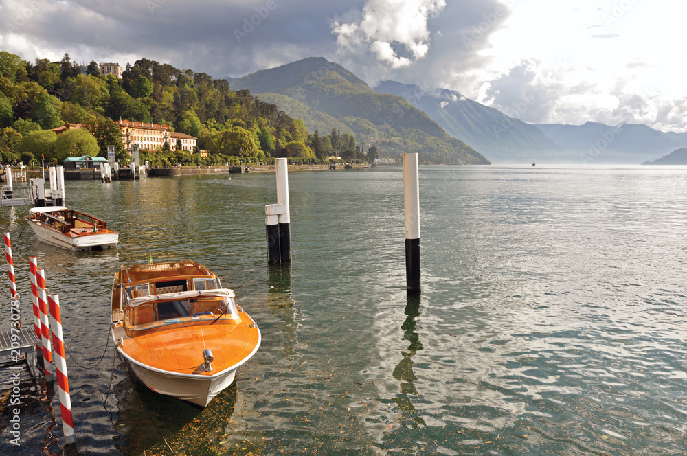 View of Lake Como in a cloudy day with motorboat and harbor in Bellagio, a charming village between the lake and the mountains of Alps. Lombardy region, northern Italy