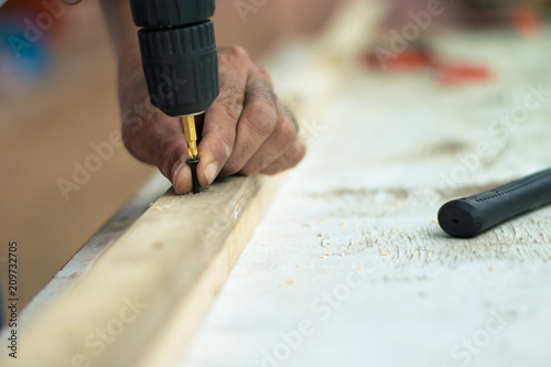 carpenter man using electric drill on worker table