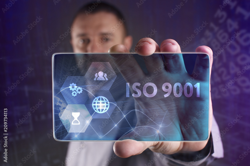 Fototapeta premium The concept of business, technology, the Internet and the network. A young entrepreneur working on a virtual screen of the future and sees the inscription: ISO 9001