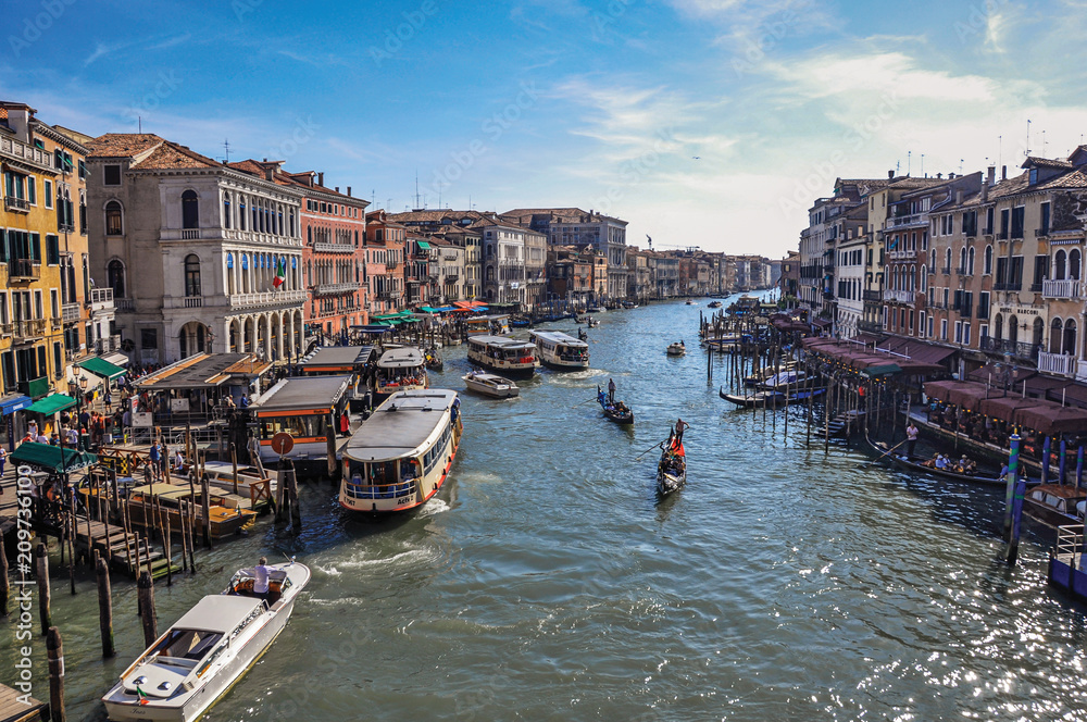 Overview of buildings, piers and gondolas in front of the Canal Grande. At the city center of Venice, the historic and amazing marine city. Veneto region, northern Italy