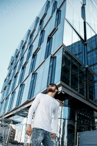 Wallpaper Mural A young man travels through the streets of the city. Boy in sunglasses Stylish man near the building. The man sits on a whip. Beard and hair in a stylish guy. Torontodigital.ca