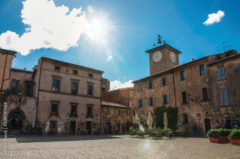 Obraz premium Square with old buildings, clock tower, shop and sunny sky in Orvieto, a pleasant and well preserved medieval town. Located in Umbria, central Italy. Retouched photo