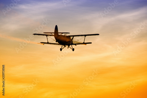 Biplane flying in vibrant sunset